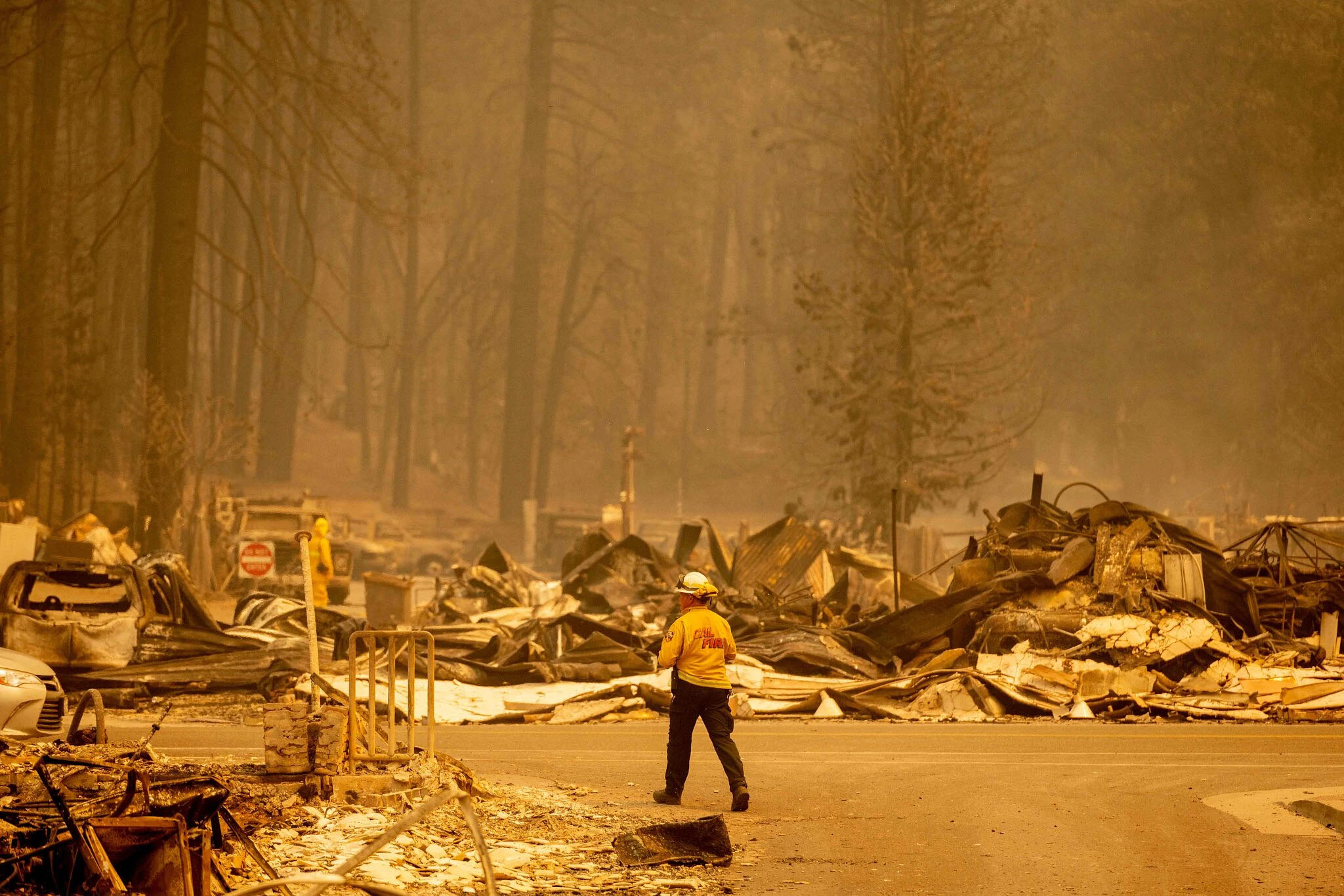 A volunteer firefighter in front of the wreckage after Dixie Fire ravaged Greenville, California.