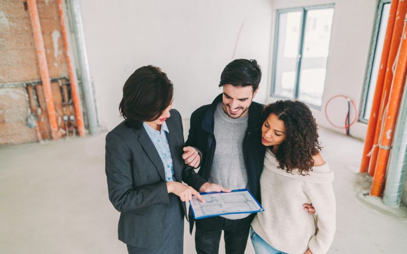 Young couple viewing new property with real estate agent